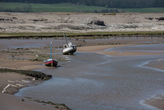 A seascape of a harbor harbour at low tide with two small boats beached in the estuary