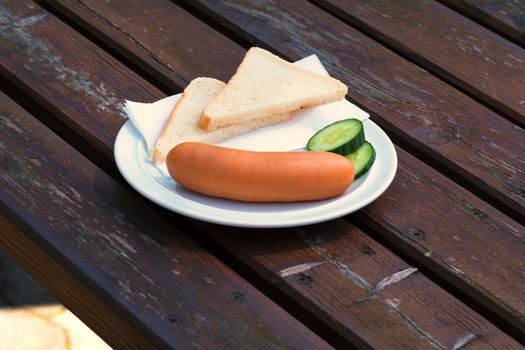 Bock sausage, wieners or Frankfurther sausage with toast and cucumbers on a white plate.