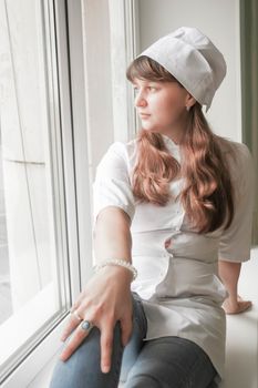 Doctor concept. A girl in a white medical gown and a cap. On the window. Photo for your design.