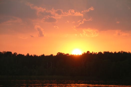 Storm clouds and sunset on forest and lake silhouette background. Nature summer sunlight wallpaper