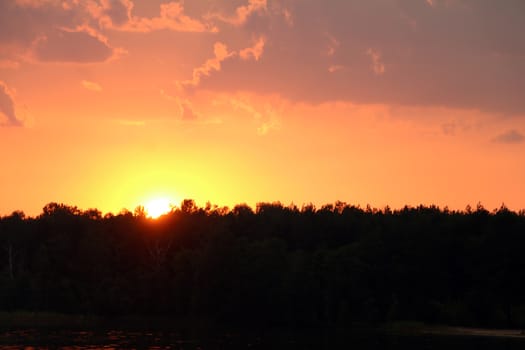 Thunderclouds sunset on forest and lake silhouette background. Nature summer sunlight wallpaper