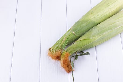 raw Corn on the white wooden background