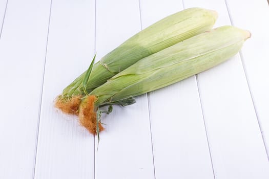 raw Corn on the white wooden background