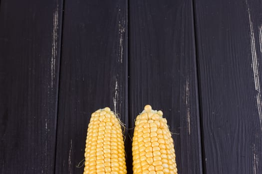 Raw corn on the black wooden board