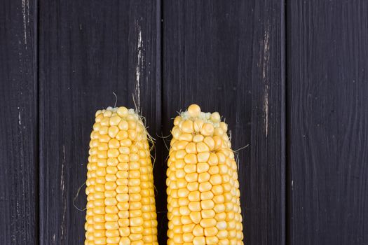 Raw corn on the black wooden board