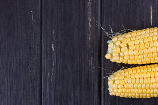 Raw corn on the black wooden board