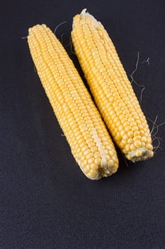 Raw corn on the black wooden board