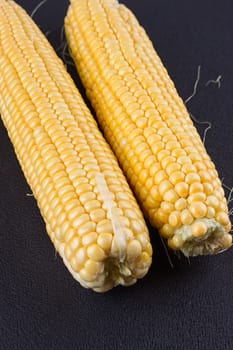 Raw corn on the black wooden board