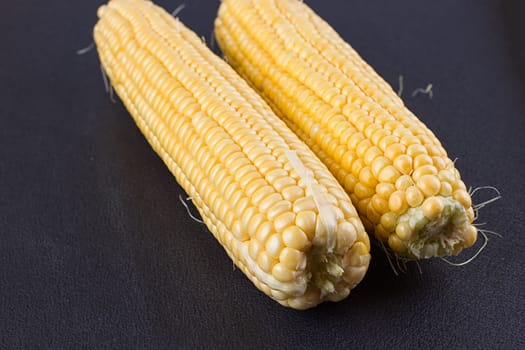 Raw corn on the black wooden board