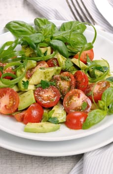 Delicate slices of avocado with tomatoes, dressed   pesto sauce.