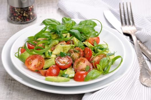 Delicate slices of avocado with tomatoes, dressed   pesto sauce.