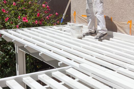 Professional Painter Rolling White Paint Onto The Top of A Home Patio Cover.