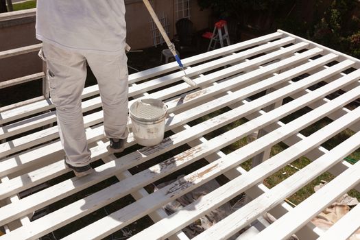 Professional Painter Rolling White Paint Onto The Top of A Home Patio Cover.