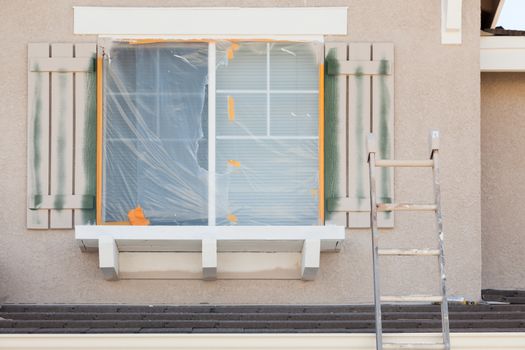 Construction Ladder Leaning Up Against A House Being Painted.