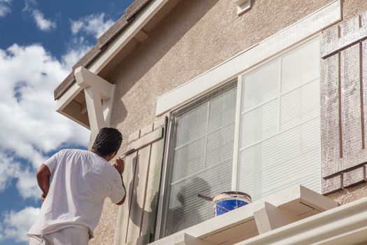 Professional House Painter Painting the Trim And Shutters of A Home.