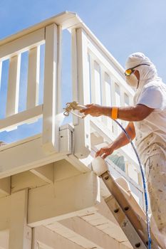 Professional House Painter Wearing Facial Protection Spray Painting Deck of A Home.