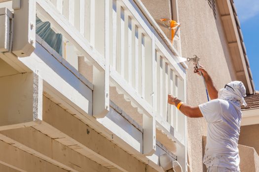 Professional House Painter Wearing Facial Protection Spray Painting Deck of A Home.