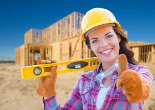 Female Construction Worker with Thumbs Up Holding Level Wearing Gloves, Hard Hat and Protective Goggles at Construction Site.