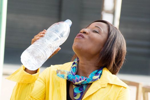 Portrait of a young woman sitting and drinking water in the bottle.