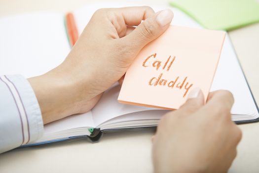 Hands holding sticky note with Call daddy text