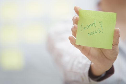 Woman holding sticky note with Good news text