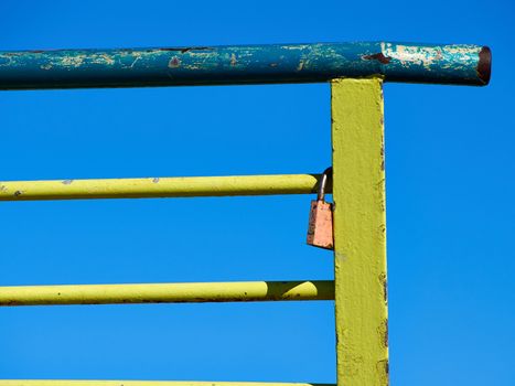 Single love lock on colorful metal rail fence with summer clear blue sky background