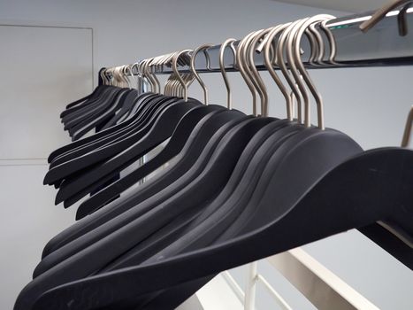 Wooden black clothes hangers on a metal rack in a wardrobe dressing room