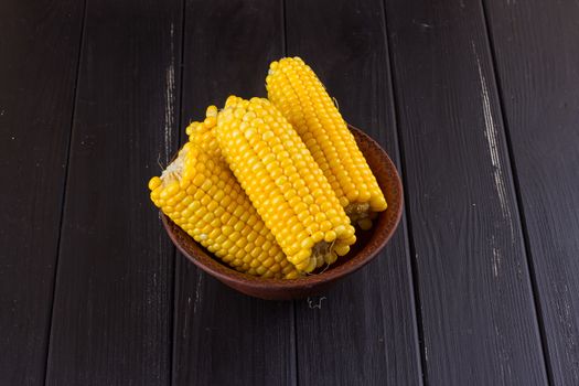 Boiled corn in a bowl on a black wooden background