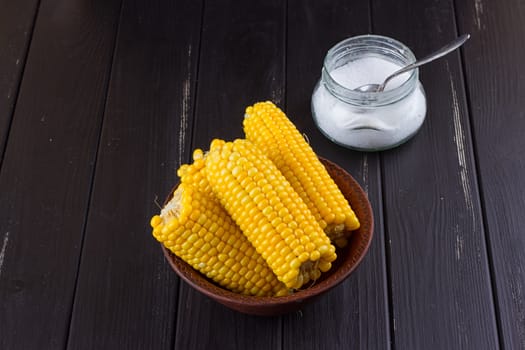 Homemade golden corn cob with salt on black background