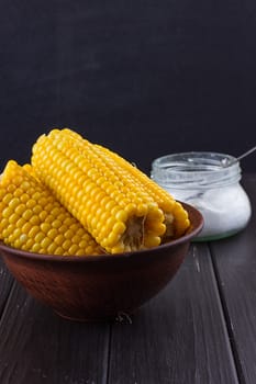 Homemade golden corn cob with salt on black background