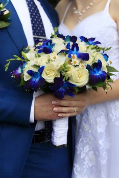 Hand of the groom and the bride with wedding bouquet