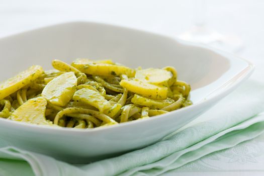 Closeup of linguine pasta with pesto genovese and potatoes over a table