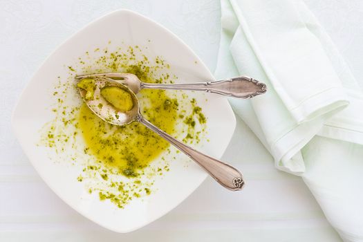 Closeup of eaten linguine pasta plate with pesto genovese, cutlery and napkin seen from above