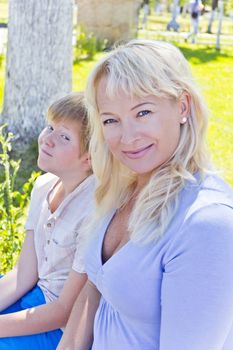 Happy blond woman and son smiling in the summer park