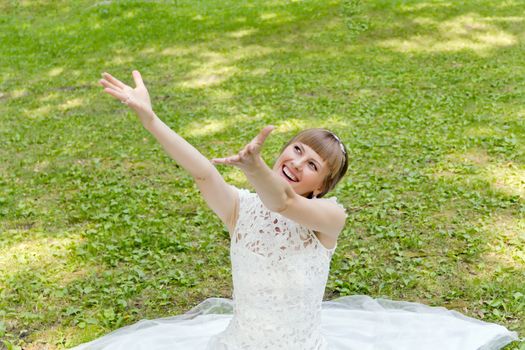 Beautiful bride in white lace dress with upwards hands