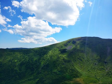 Peaceful green mountains covered of grass and trees under the clear blue sky