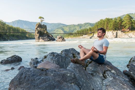 Young man spending time at riverbank of mountain river