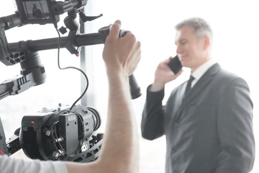 Videographer using steadycam, making video of businessman talking on phone