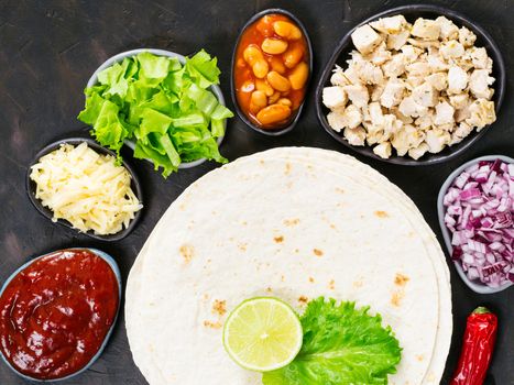 Traditional mexican tortilla with mix of ingredients on black concrete background