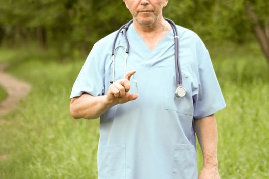 Doctor concept. The doctor in the medical dressing gown holds a whisker finger. Photo horizontal for your design. Against the background of nature.