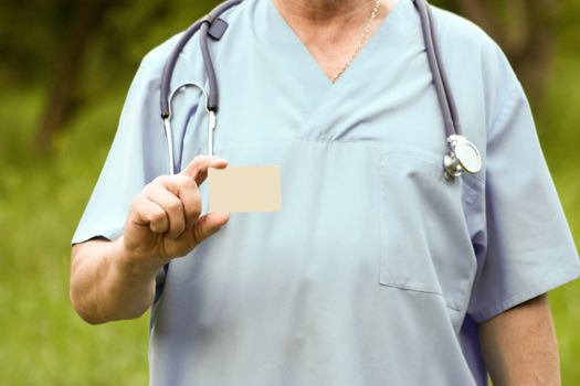 Doctor concept. A doctor in a medical gown keeps a gold card. Photo horizontal for your design. Against the background of nature.