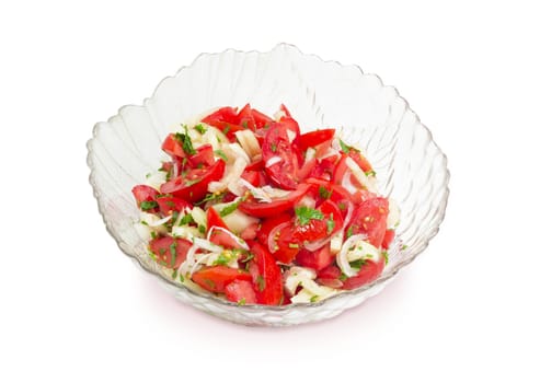 Vegetable salad of a fresh sliced tomatoes, white bell pepper, onion and potherb in a glass salad bowl on a white background
