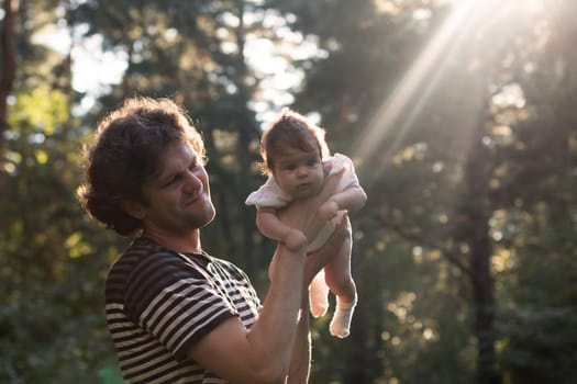 Happy joyful father having fun throws up in the air his child against the sunset background - intentional sun glare and vintage color, lens focus on father. Father's day. Film filter.