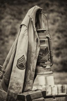 Vintage retro sepia photograph of a US army sergeant jacket from WW2 hanging on a later in an upright vertical format