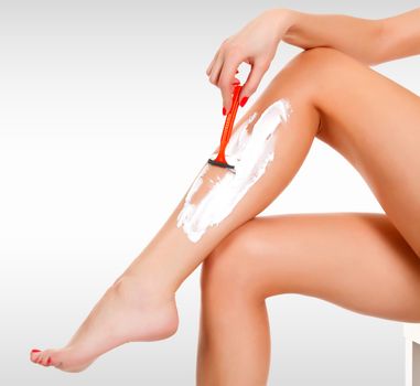 Closeup shot of woman's legs. Girl shaving her leg against a grey background with copyspace