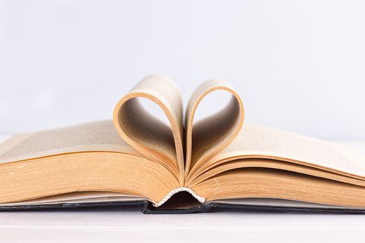 Pages of a book curved into a heart shape on white background