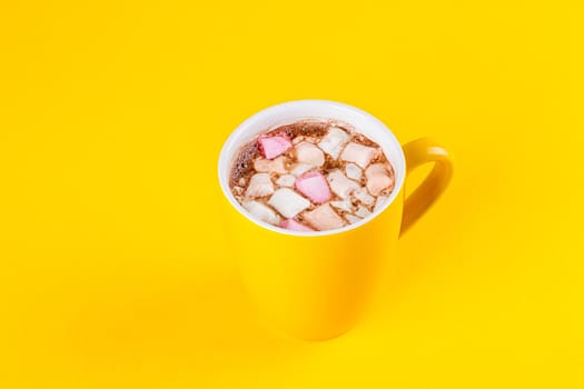 Yellow cup of hot cocoa with marshmallows on yellow background