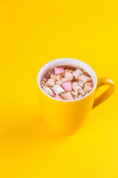 Yellow cup of hot cocoa with marshmallows on yellow background