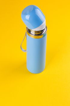 Blue thermos for hot drinks on a yellow background