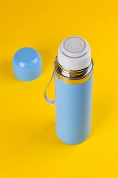 Blue thermos for hot drinks on a yellow background